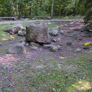 Dobumakmeņu grupa meža klajumā ar lielu laukakmeni un soliņiem Dobumakmeņu grupa meža klajumā ar lielu laukakmeni un soliņiem