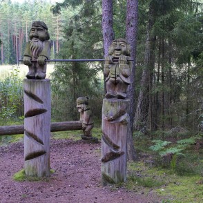 Wooden sculptures by a forest obstacle with a log between posts Wooden sculptures by a forest obstacle with a log between posts