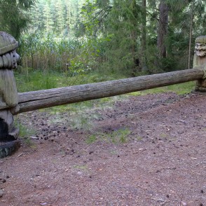 Wooden sculptures with a long log in a forest clearing near reeds Wooden sculptures with a long log in a forest clearing near reeds