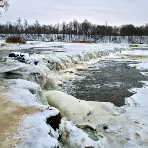 Frozen Venta waterfall in winter with ice formations and open river flow Frozen Venta waterfall in winter with ice formations and open river flow