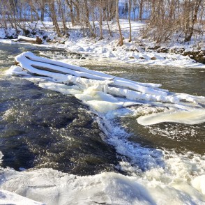 Abava Rumba waterfall in winter with frozen logs and rushing river Abava Rumba waterfall in winter with frozen logs and rushing river