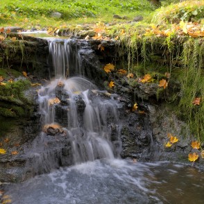 Rumbiņas ūdenskrituma tuvplāns ar rudens lapām un tekošu ūdeni Rumbiņas ūdenskrituma tuvplāns ar rudens lapām un tekošu ūdeni