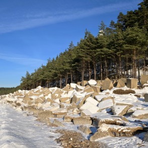 Concrete coastal reinforcements and Užava lighthouse in winter landscape Concrete coastal reinforcements and Užava lighthouse in winter landscape