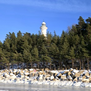 View of the white Užava lighthouse from the frozen seashore View of the white Užava lighthouse from the frozen seashore