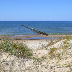Sand dunes and a wooden pier by a calm sea Sand dunes and a wooden pier by a calm sea