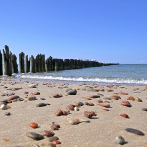 Sandy beach with pebbles and a wooden pier in the sea Sandy beach with pebbles and a wooden pier in the sea