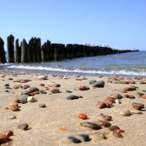 Sandy beach with pebbles and a softly blurred wooden pier Sandy beach with pebbles and a softly blurred wooden pier