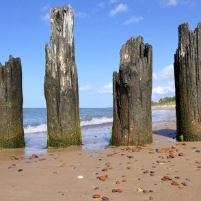 Old wooden posts by the sea with waves and pebbles Old wooden posts by the sea with waves and pebbles