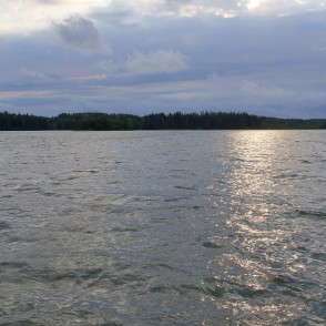 Plateļu ezera plašums ar saules atspīdumu uz viļņota ūdens un meža horizontu Plateļu ezera plašums ar saules atspīdumu uz viļņota ūdens un meža horizontu