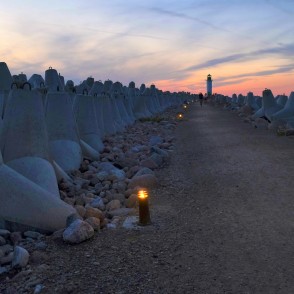 Sunset at Ventspils Southern Pier with lighthouse and lit pathway Sunset at Ventspils Southern Pier with lighthouse and lit pathway