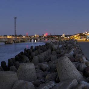 Ventspils Dienvidu mola promenāde krēslā ar ostu un skulptūru Govs Matrozis Ventspils Dienvidu mola promenāde krēslā ar ostu un skulptūru Govs Matrozis