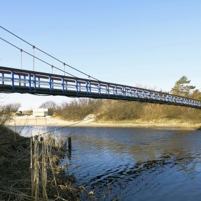 Sventājas Pērtiķu piekares tilts pāri upei plašā ainavā Sventājas Pērtiķu piekares tilts pāri upei plašā ainavā