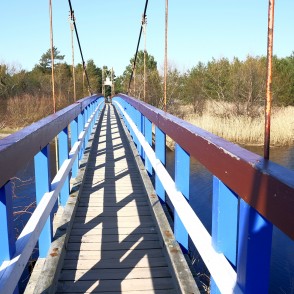 Skats pa Sventājas Pērtiķu tiltu ar zilām margām virs upes Skats pa Sventājas Pērtiķu tiltu ar zilām margām virs upes