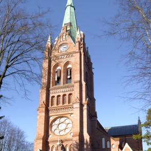 Baznīcas tornis Palangā ar pulksteni un augstu smaili saulainā dienā Baznīcas tornis Palangā ar pulksteni un augstu smaili saulainā dienā