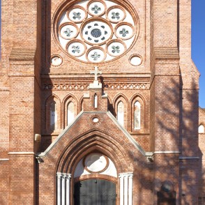 Palangas baznīcas ieeja ar ķieģeļu arku un rozetes logu fasādē Palangas baznīcas ieeja ar ķieģeļu arku un rozetes logu fasādē