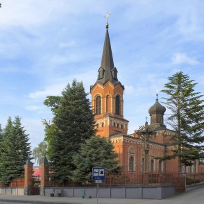 Marijampoles baznīcas tornis un sīpolkupols ar krucifiksu priekšplānā Marijampoles baznīcas tornis un sīpolkupols ar krucifiksu priekšplānā