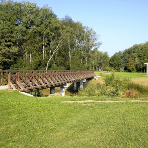 Wooden pedestrian bridge over a small river in an open Skuodas city park Wooden pedestrian bridge over a small river in an open Skuodas city park