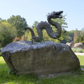 Metal dragon sculpture on a boulder in the stone park Metal dragon sculpture on a boulder in the stone park