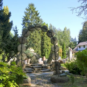Stone garden gate with millstones and steps in a green park setting Stone garden gate with millstones and steps in a green park setting