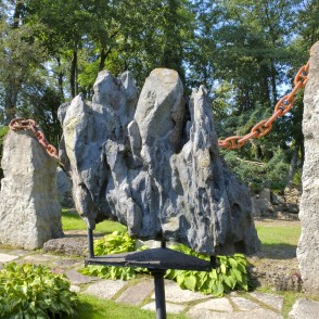 Stone sculpture with a rusted chain between large stone pillars in a garden Stone sculpture with a rusted chain between large stone pillars in a garden