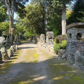 Gravel path in a garden with stone wall, pillars and colorful chains Gravel path in a garden with stone wall, pillars and colorful chains