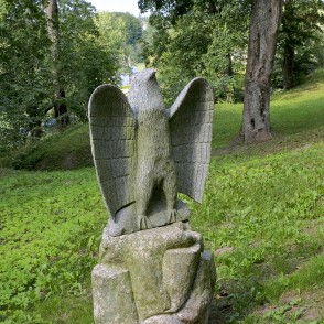 Stone bird sculpture in Salantai City Park among trees Stone bird sculpture in Salantai City Park among trees