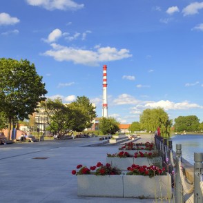Danes upes promenāde ar ziedu kastēm, rotaļu laukumu un skatu uz rūpniecisko skursteni Danes upes promenāde ar ziedu kastēm, rotaļu laukumu un skatu uz rūpniecisko skursteni